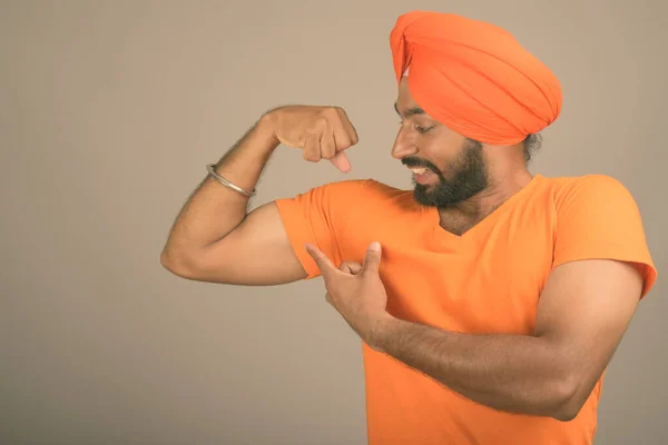 Jovem bonito indiana sikh homem vestindo turbante contra cinza fundo — Fotografia de Stock