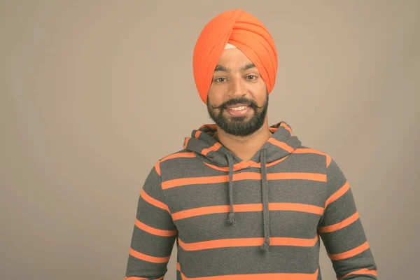 Young handsome Indian Sikh man wearing turban against gray background — Stock Photo, Image