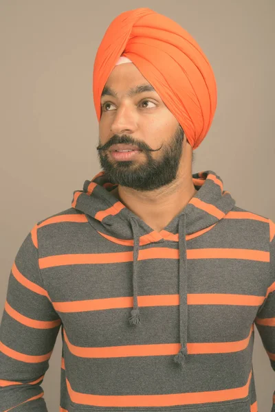 Ung vacker indisk sikh man bär turban mot grå bakgrund — Stockfoto