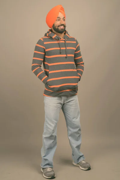 Jonge knappe Indiase Sikh man met tulband tegen grijze achtergrond — Stockfoto