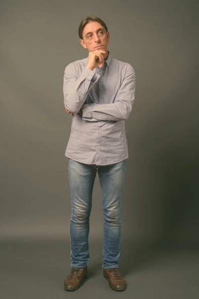 Mature handsome Italian man against gray background