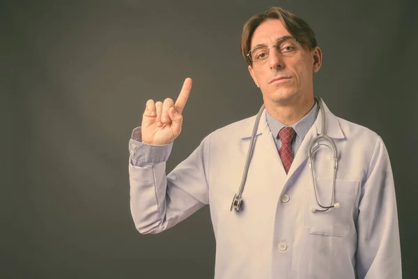 Reif hübsch italienisch mann doktor vor grauem hintergrund — Stockfoto