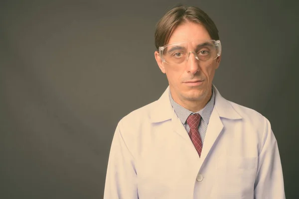 Olgun yakışıklı İtalyan doktor gri arka planda koruyucu gözlük takıyor. — Stok fotoğraf