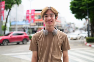 Kulaklıklı yakışıklı Asyalı genç Taylandlı yaz boyunca modern yaşam tarzının tadını çıkarıyor.