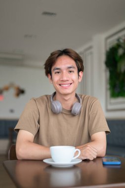 Kulaklıklı yakışıklı Asyalı genç Taylandlı modern yaşam tarzını seviyor.