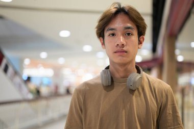 Kulaklıklı yakışıklı Asyalı genç Taylandlı modern yaşam tarzını seviyor.