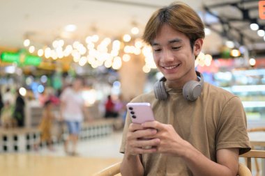 Kulaklıklı yakışıklı Asyalı genç Taylandlı modern yaşam tarzını seviyor.