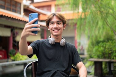 Geleneksel Çin bahçe pazarında oturan Taylandlı genç bir adam. Çeşitli kavramlar ve kullanımlar için kendine güvenen, rahat ve otantik görünüm