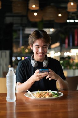 Tayland 'da Tayland erişteleri genç turistler tarafından yemek çubuklarıyla yenir. Asya 'da turistler ve yerliler tarafından sevilen ünlü sokak yemekleri..