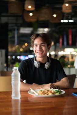 Tayland 'da Tayland erişteleri genç turistler tarafından yemek çubuklarıyla yenir. Asya 'da turistler ve yerliler tarafından sevilen ünlü sokak yemekleri..