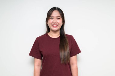 Beyaz arka planda gülümseyen, sıradan tişörtler giyen Asyalı bir kadının stüdyo portresi.