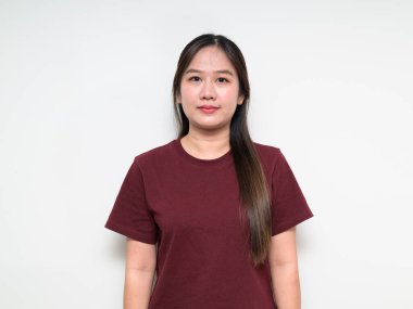 Beyaz arka planda sıradan tişörtler giyen Asyalı genç bir kadının stüdyo portresi.