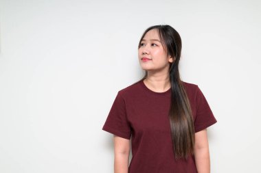 Beyaz arka planda gelişigüzel tişört giyen Asyalı genç bir kadının stüdyo portresi.