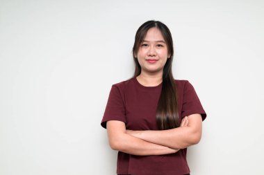 Asyalı genç bir kadının stüdyo portresi beyaz arkaplan üzerinde günlük tişört ile çaprazlanmış.