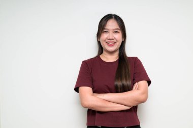 Asyalı genç bir kadının stüdyo portresi beyaz arkaplan üzerinde günlük tişört ile çaprazlanmış.