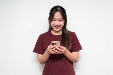 Beyaz arka planda cep telefonu kullanan Asyalı genç bir kadının atölye portresi.