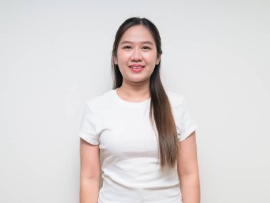 Sıradan beyaz tişört giyen Asyalı genç bir kadının stüdyo portresi.