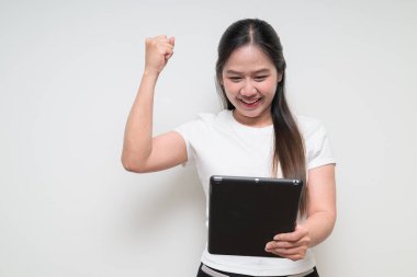 Sade beyaz tişört giyen ve dijital tablet bilgisayar kullanan Asyalı genç bir kadının stüdyo portresi.