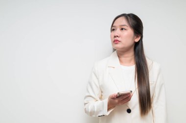 Takım elbise giyen genç Asyalı kadının stüdyo portresi beyaz arka planda cep telefonuyla iş yapmaya hazır.