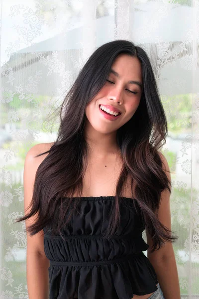 Güzel Asyalı bir kadının portresi. Gözleri kapalı gülümsüyor ve gülüyor.