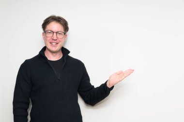 İskandinav orta yaşlı adam beyaz stüdyo arka planında siyah süveter içinde gülümsüyor.