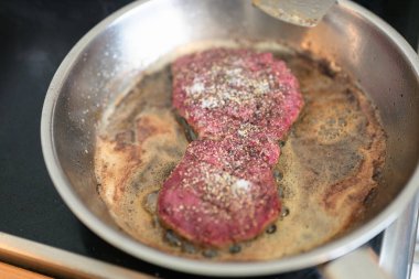 Biftekli kızartma tavası evde yakın plan çekimde pişiriliyor.