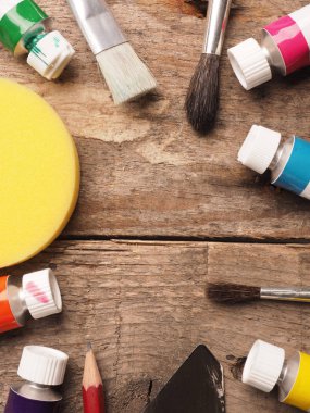 Sanatsal ressam gereçleri ahşap bir masanın üzerinde, ortasında yazı veya resim için yer var.