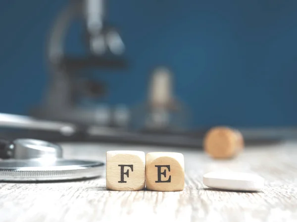 Düzenli olarak masaya steteskop, sağlık hizmeti veya tıbbi konsept konsept konulu küçük tahta bloklar üzerinde demir sözcüğü