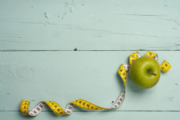 Świeże zielone jabłuszko z miara zwijana na drewno — Zdjęcie stockowe