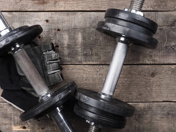 Gloves with dumbbells on wood, top view — Stock Photo, Image