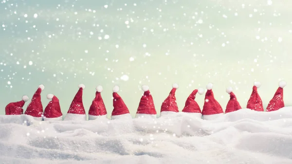Many hats of Santa in a row with snow — Stock Photo, Image
