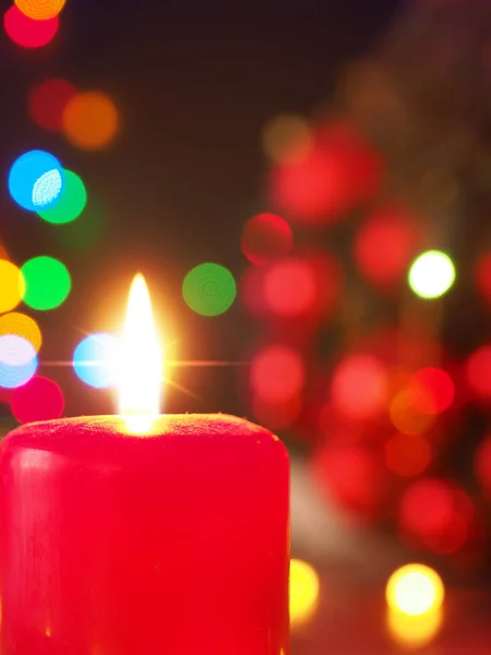 Płonąca świeca adwentowa z lampkami świątecznymi — Zdjęcie stockowe