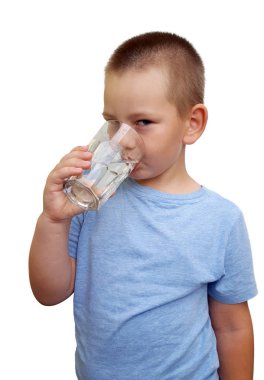 Beyaz arka planda camdan su içen tatlı bir çocuk.
