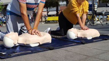 People learning how to make first aid heart compressions clipart