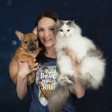 Kollarında kedi ve köpek yavrusu olan genç bir kadın.
