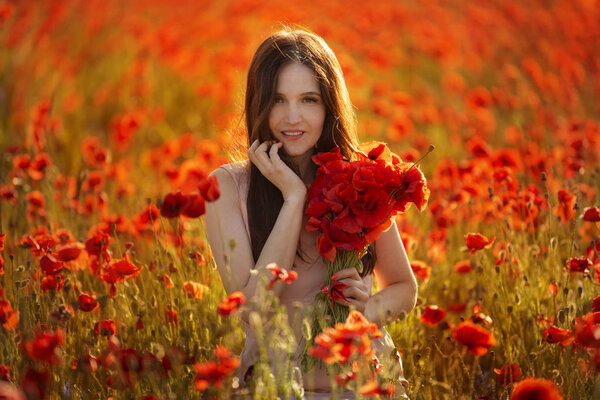 Молодая девушка в поле с красными маками
