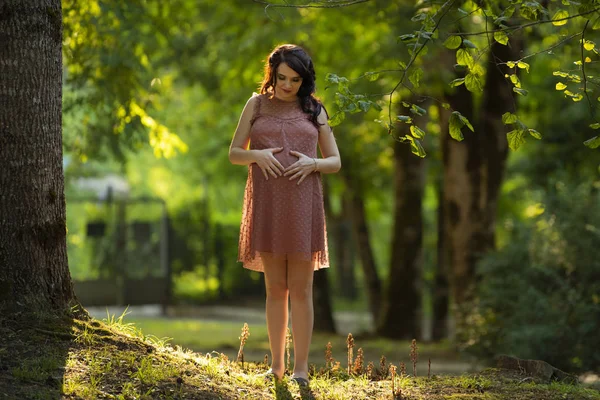 Gravid flicka i klänning promenader genom skogen — Stockfoto