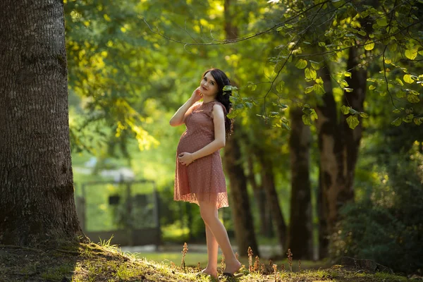 Беременная девушка в платье гуляет по лесу — стоковое фото