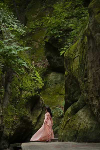 Menina em um vestido em um fundo de pedras — Fotografia de Stock