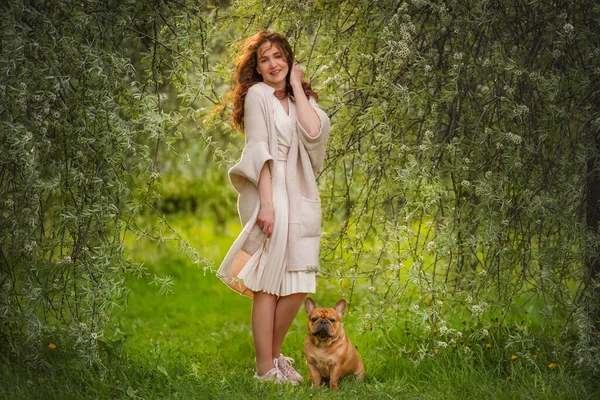 若い女性と犬フランスのブルドッグは隔離後の晴れた日に公園を歩きます ストック画像