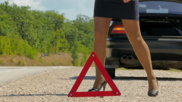 Una mujer camina junto a un triángulo de advertencia — Vídeo de stock