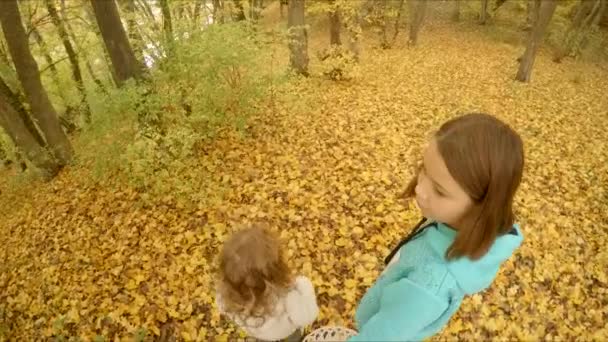 Crianças caminham ao longo da folhagem amarela — Vídeo de Stock