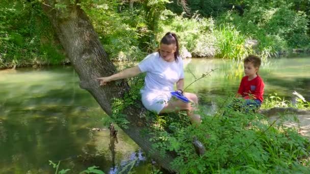 Die Frau erklärt dem Kind, wie man ein ferngesteuertes Boot bedient — Stockvideo