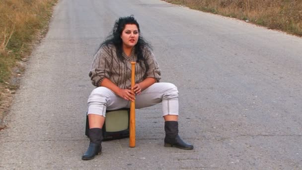 La grosse fille est assise à la télé et tient une batte. Mouvement lent . — Video