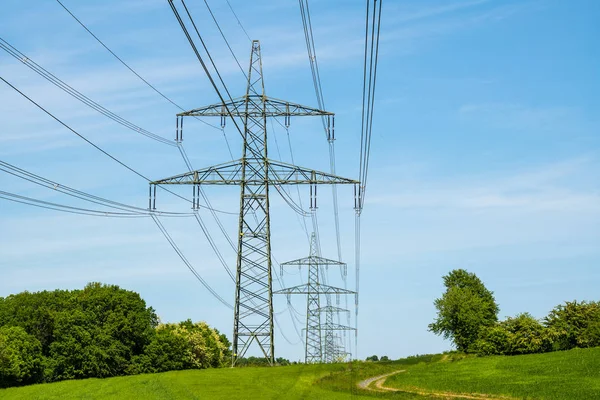 Postes de eletricidade em um prado verde — Fotografia de Stock