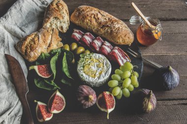 camembert peyniri, incir, jamon, bal ve ev yapımı ekmek, rustik ahşap arka plan üzerinde koyu hizmet kurulu
