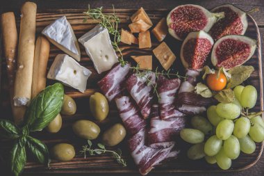  incir, camembert peyniri, salam, zeytin, üzüm rustik ahşap arka plan üzerinde koyu hizmet gemide. yukarıdan görüntülemek