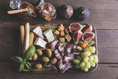 incir, camembert peyniri, salam, zeytin, üzüm rustik ahşap arka plan üzerinde koyu hizmet gemide. Üstten görünüm 
