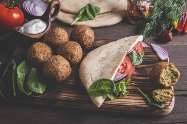 Falafel, taze sebze, sos ve Pide tahta masada ekmek