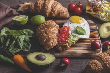 kruvasan guacamole avokado, kızarmış yumurta ve domates, ıspanak yaprakları. vejetaryen tabağı